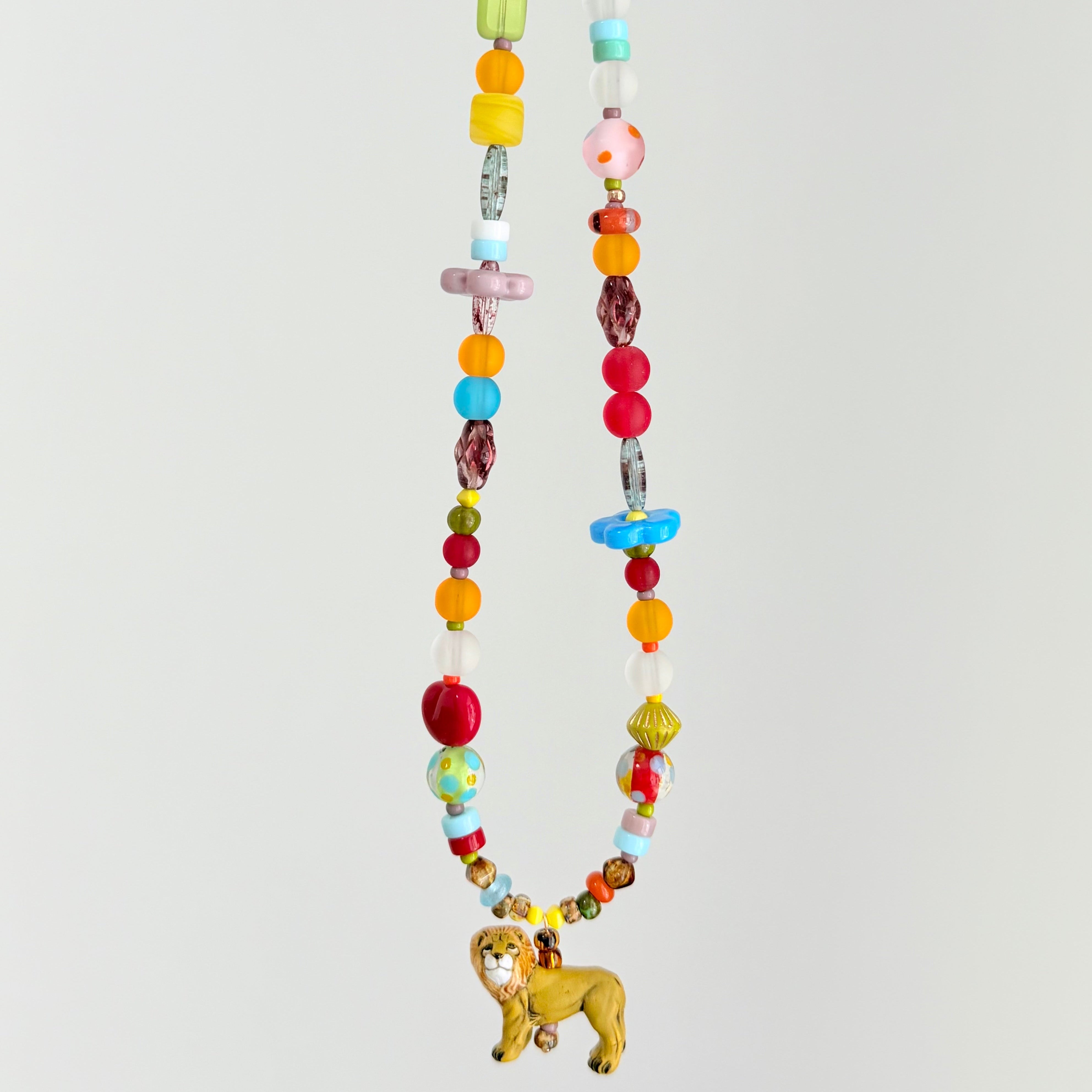 Colorful beaded necklace with a lion charm on a light gray background